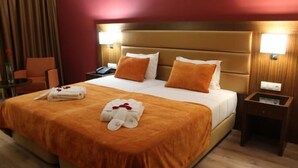 Une chambre d’hôtel avec un grand lit, deux oreillers, une table de chevet et une chaise.
