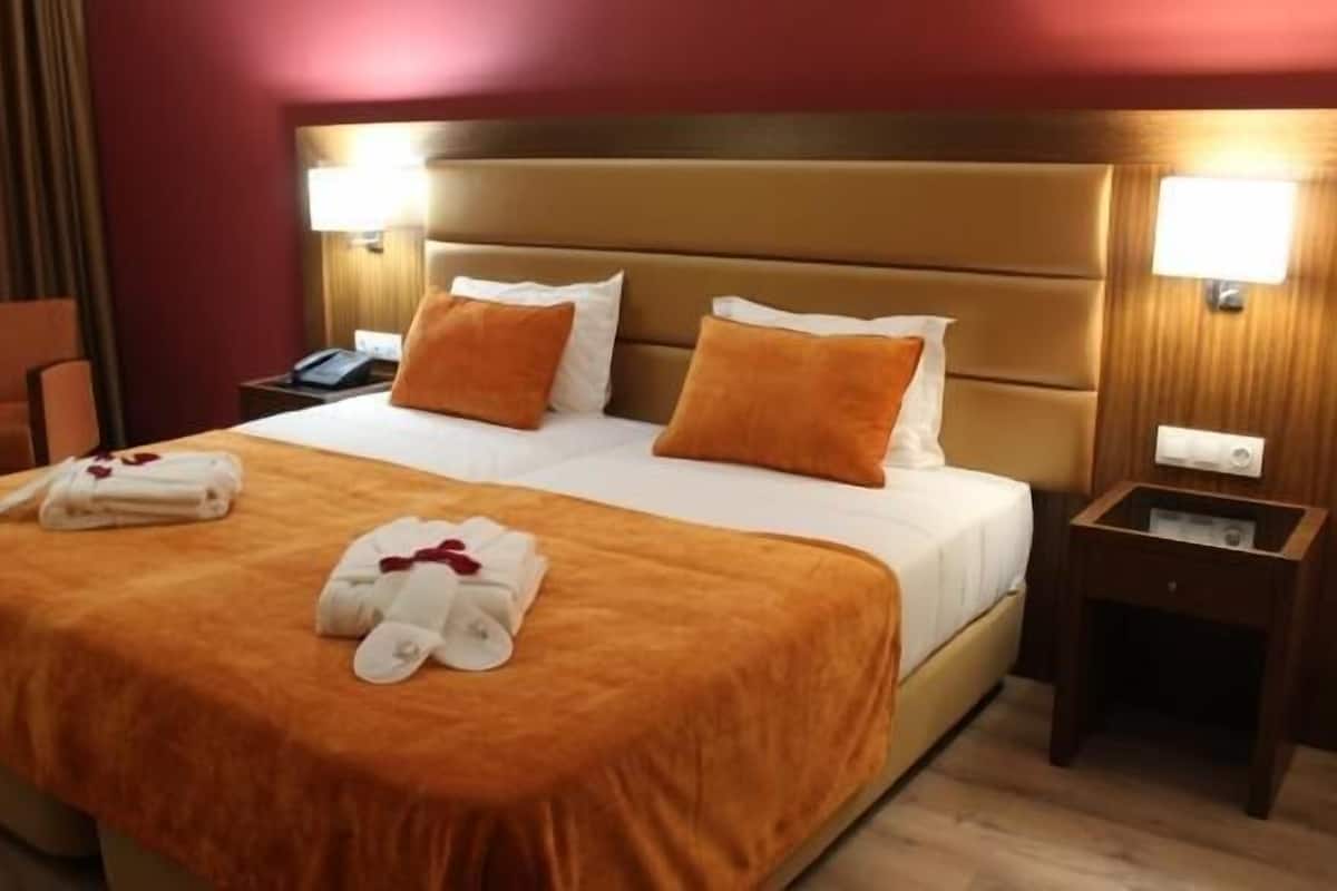 Una habitación de hotel con una cama grande, dos almohadas, una mesita de noche y una silla.