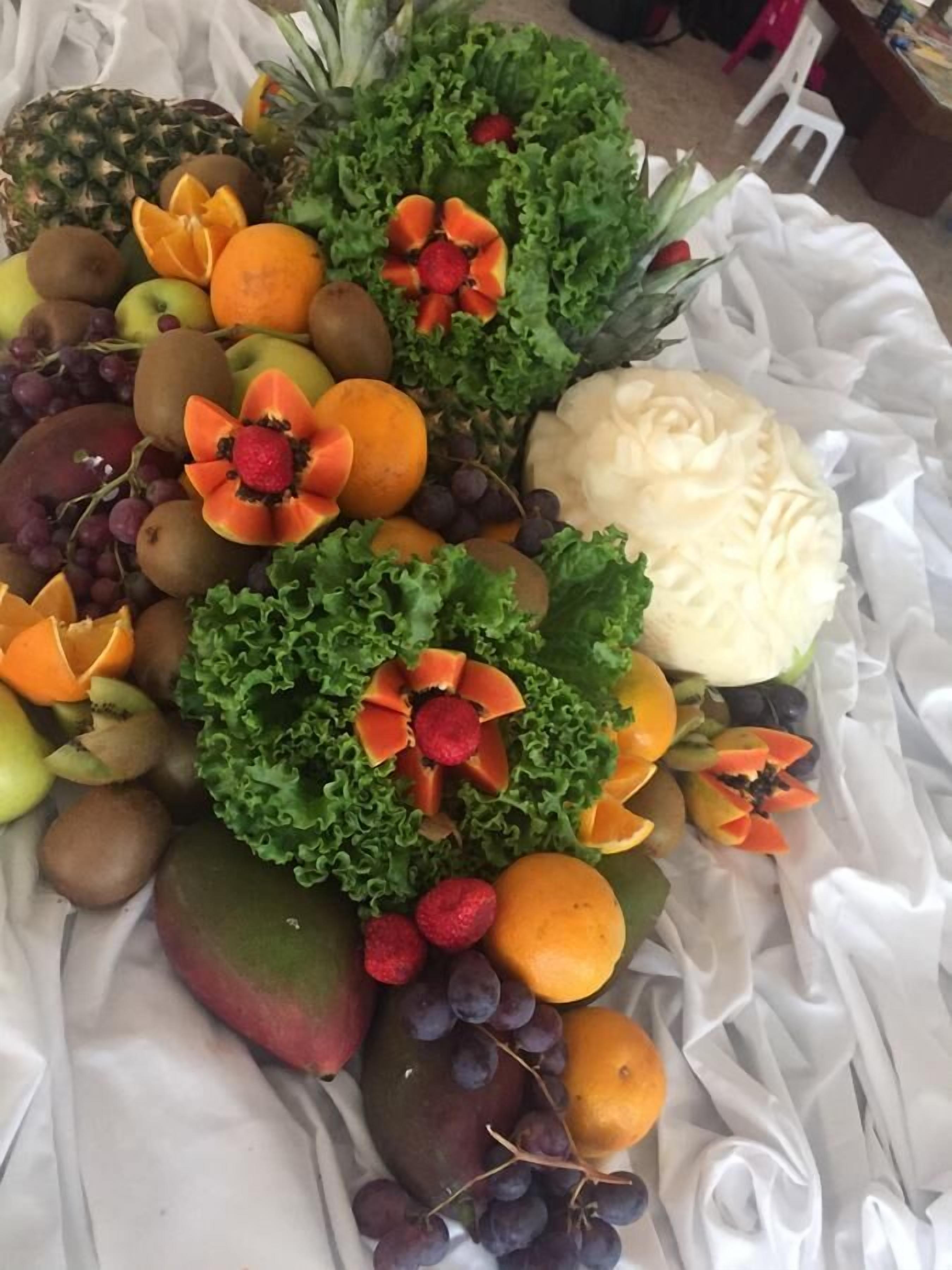 Una bandeja de frutas con diversas frutas y una piña tallada como pieza central.