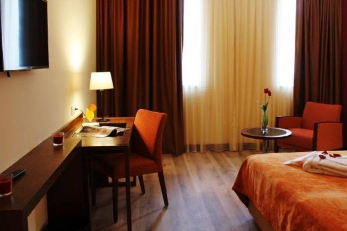 Habitación de hotel con una cama, un escritorio, una silla, una mesita y un televisor.