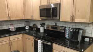 A kitchen with wooden cabinets, a black countertop, a stainless steel microwave, a coffee maker, and a blender. - Cozy, Quiet and Well Appointed Dual Master w/  2.5 ba Townhome 4 miles to GSO!! (Greensboro)