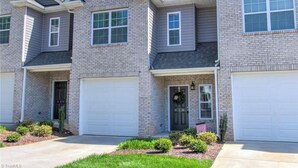 A row of townhouses with attached garages, a front porch, and a small front yard. - Cozy, Quiet and Well Appointed Dual Master w/  2.5 ba Townhome 4 miles to GSO!! (Greensboro)
