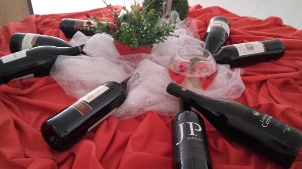 Une table sur laquelle sont disposées plusieurs bouteilles de vin et un verre, le tout posé sur une nappe rouge, avec une petite plante en pot à proximité.