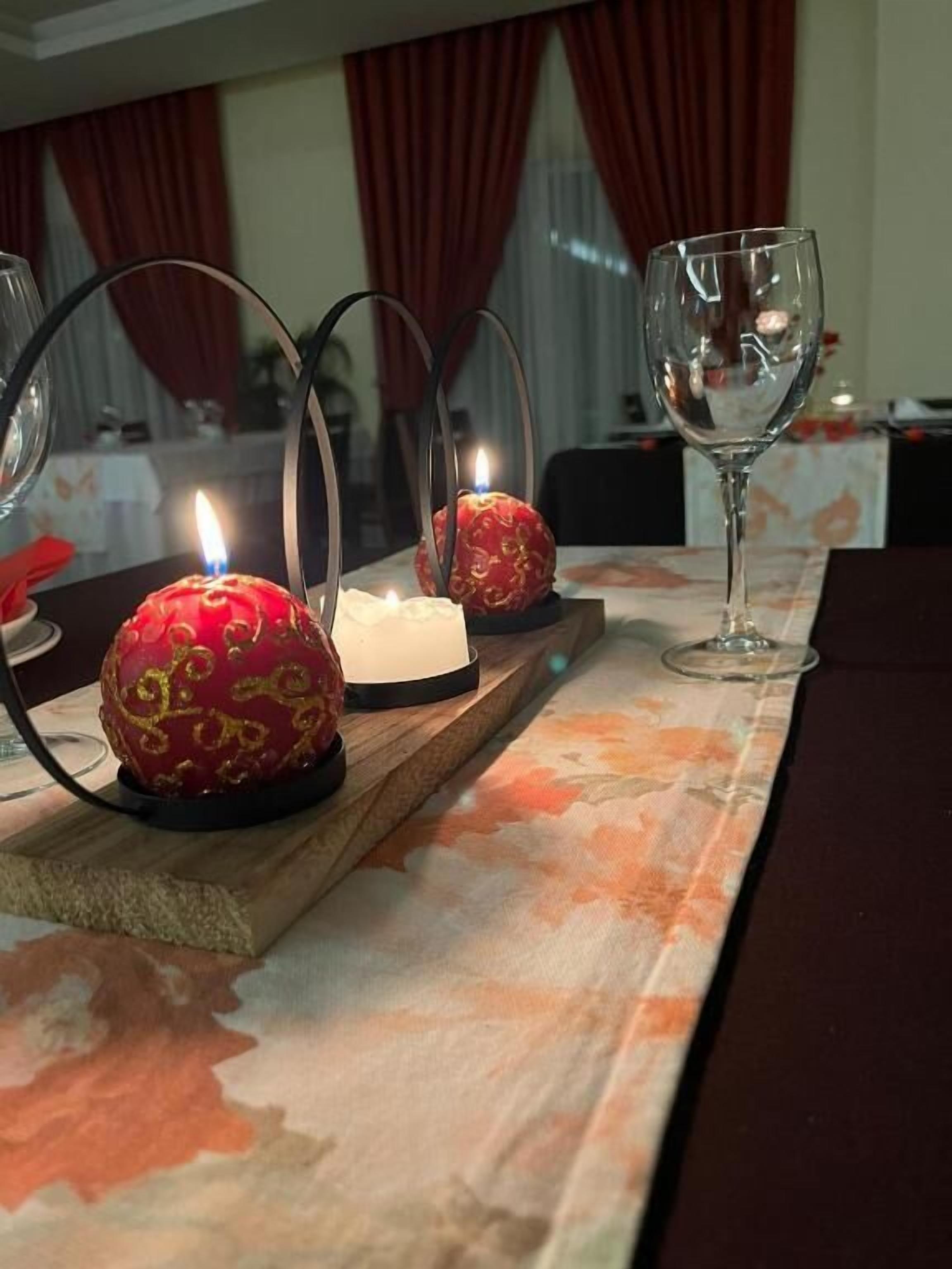 Una mesa con velas y una copa sobre un mantel.