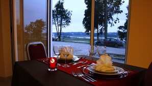 Une table dressée pour deux personnes, avec une nappe rouge, des assiettes blanches et de la verrerie transparente.