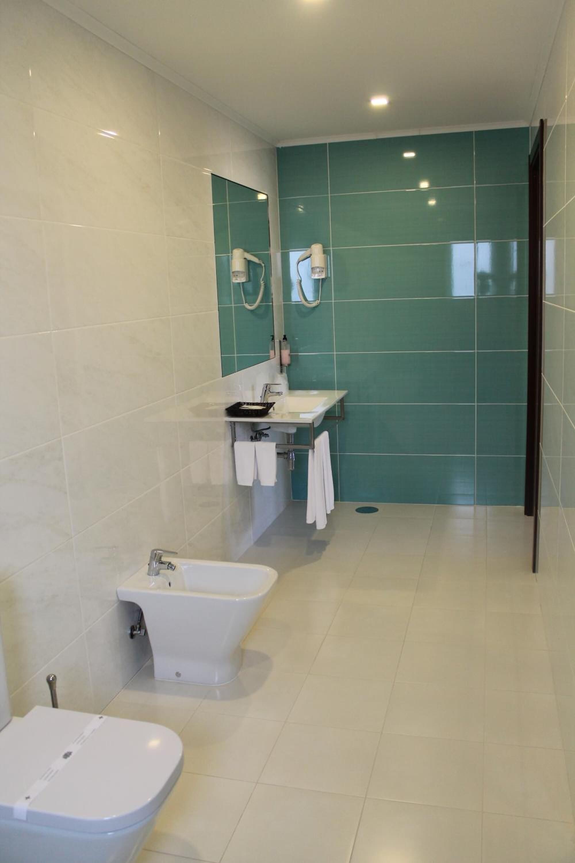 A modern bathroom with a toilet, bidet, and sink.