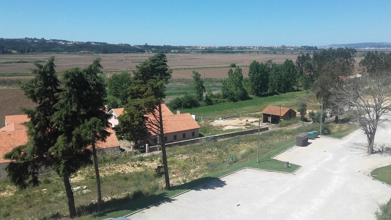 Et boligområde med huse, en belagt vej og åbne marker.