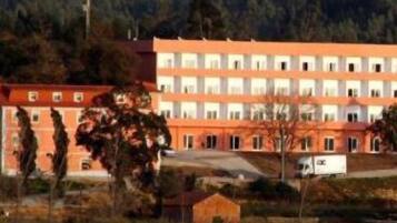 Um edifício de vários andares com fachada uniforme, possivelmente um hotel ou complexo residencial, localizado numa encosta com vista ampla da paisagem circundante.