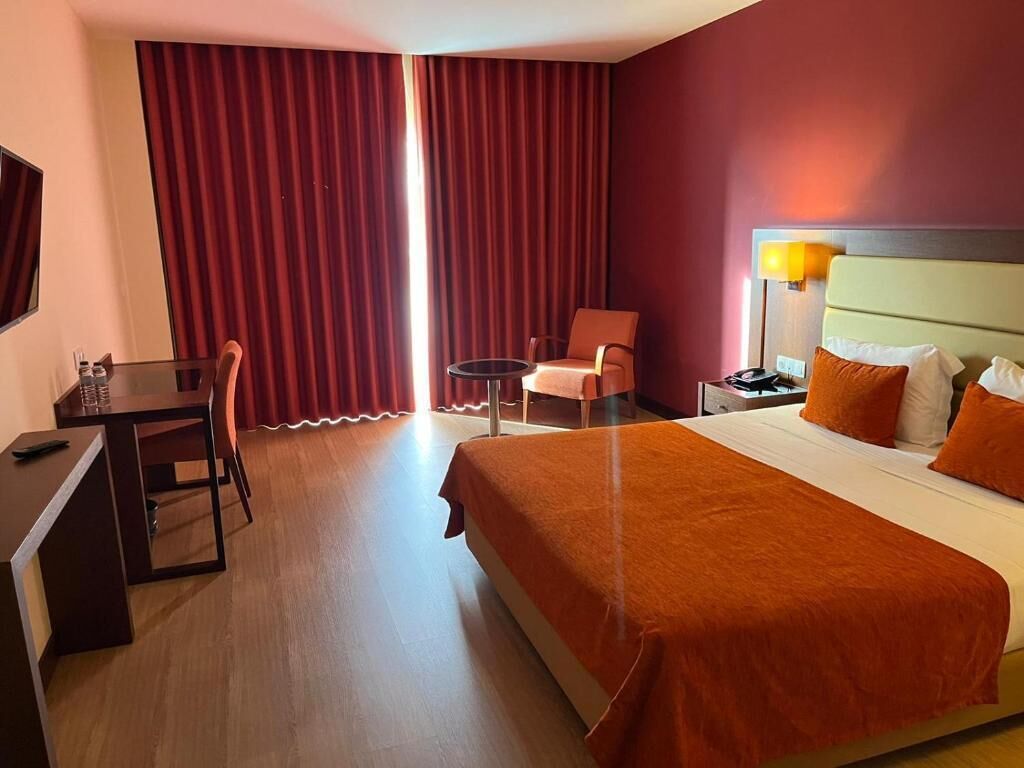 Ett hotellrum med en säng, ett skrivbord, en stol och ett litet bord.