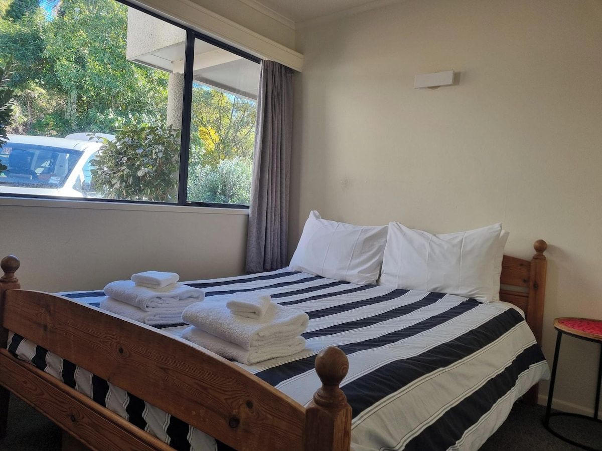 A hotel room with a bed, a window, and a view of the outside.