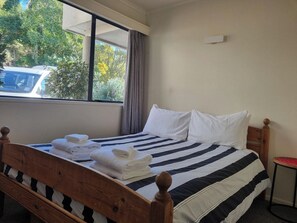 A hotel room with a bed, a window, and a view of the outside.