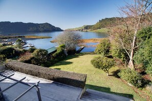 Una propiedad junto al lago con muelle de madera, césped y vistas al lago y las colinas.