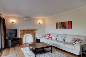 A living room with a fireplace, a sofa, a coffee table, and two wall-mounted lamps.
