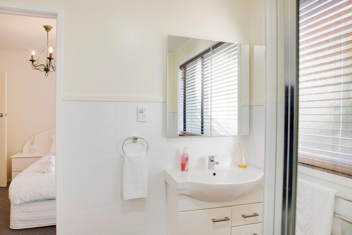Een badkamer met een wit wastafelmeubel, spiegel en handdoekhouder.