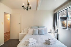 A bedroom with a bed, bedside table, and a window with curtains.