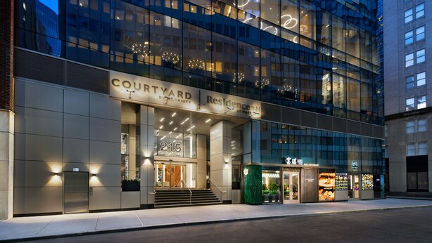A modern hotel with a glass facade, a visible entrance, and a sign indicating it is a Courtyard by Marriott. - Residence Inn by Marriott New York Downtown Manhattan/Financial District (New York)