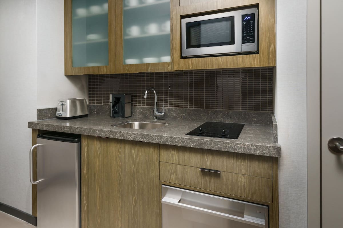 A modern kitchen with a stainless steel refrigerator, a built-in microwave, a toaster, and a dishwasher.