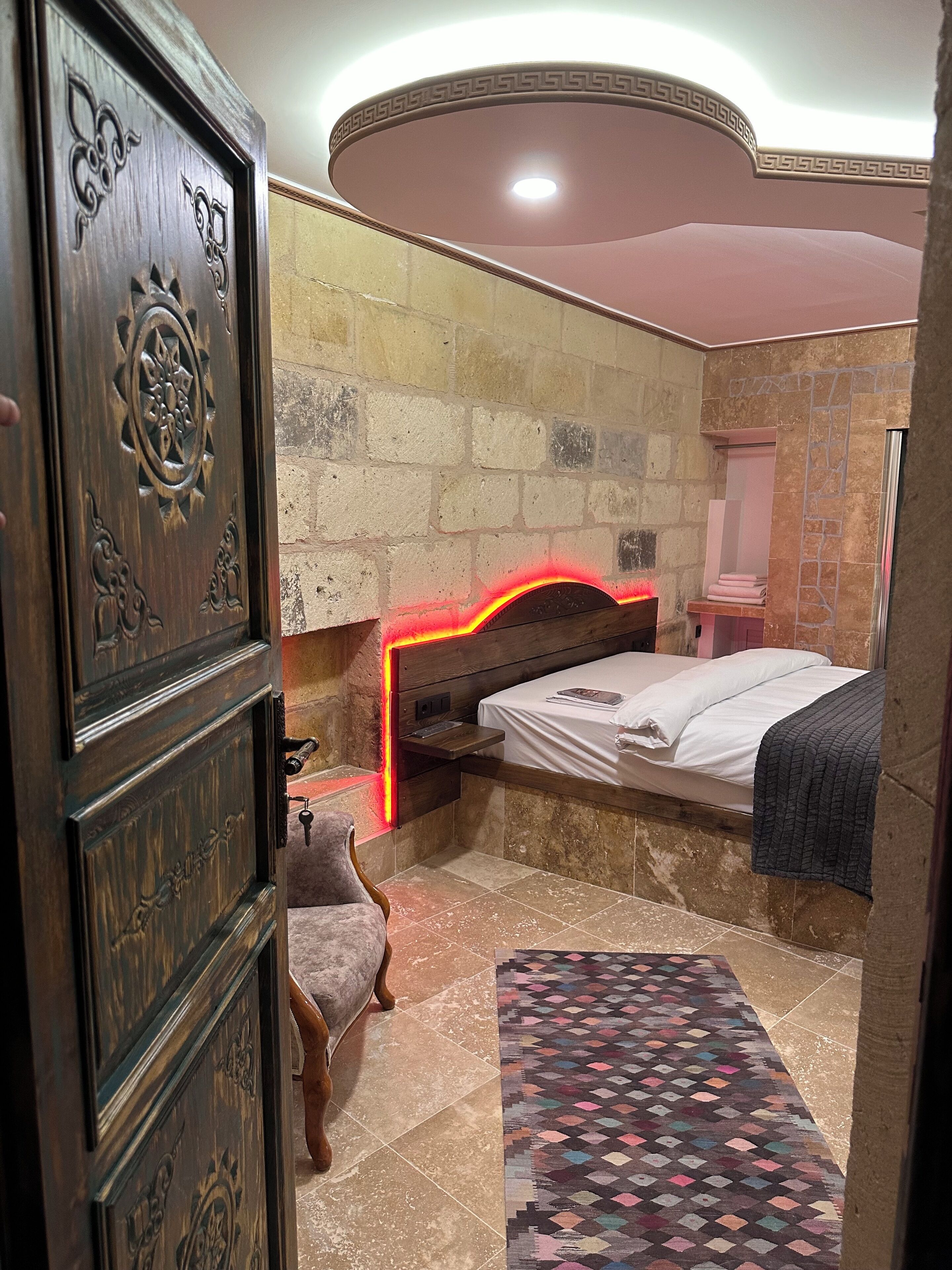 Un dormitorio con una cama, una mesita de noche, un aparador y una alfombra estampada.