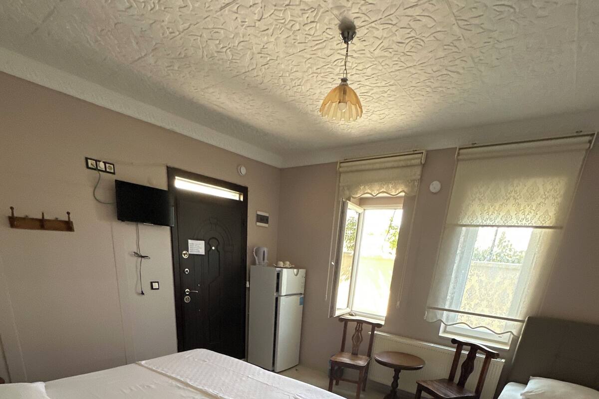 Habitación con dos camas, una mesita, una silla, refrigerador, televisión y una alfombra estampada.