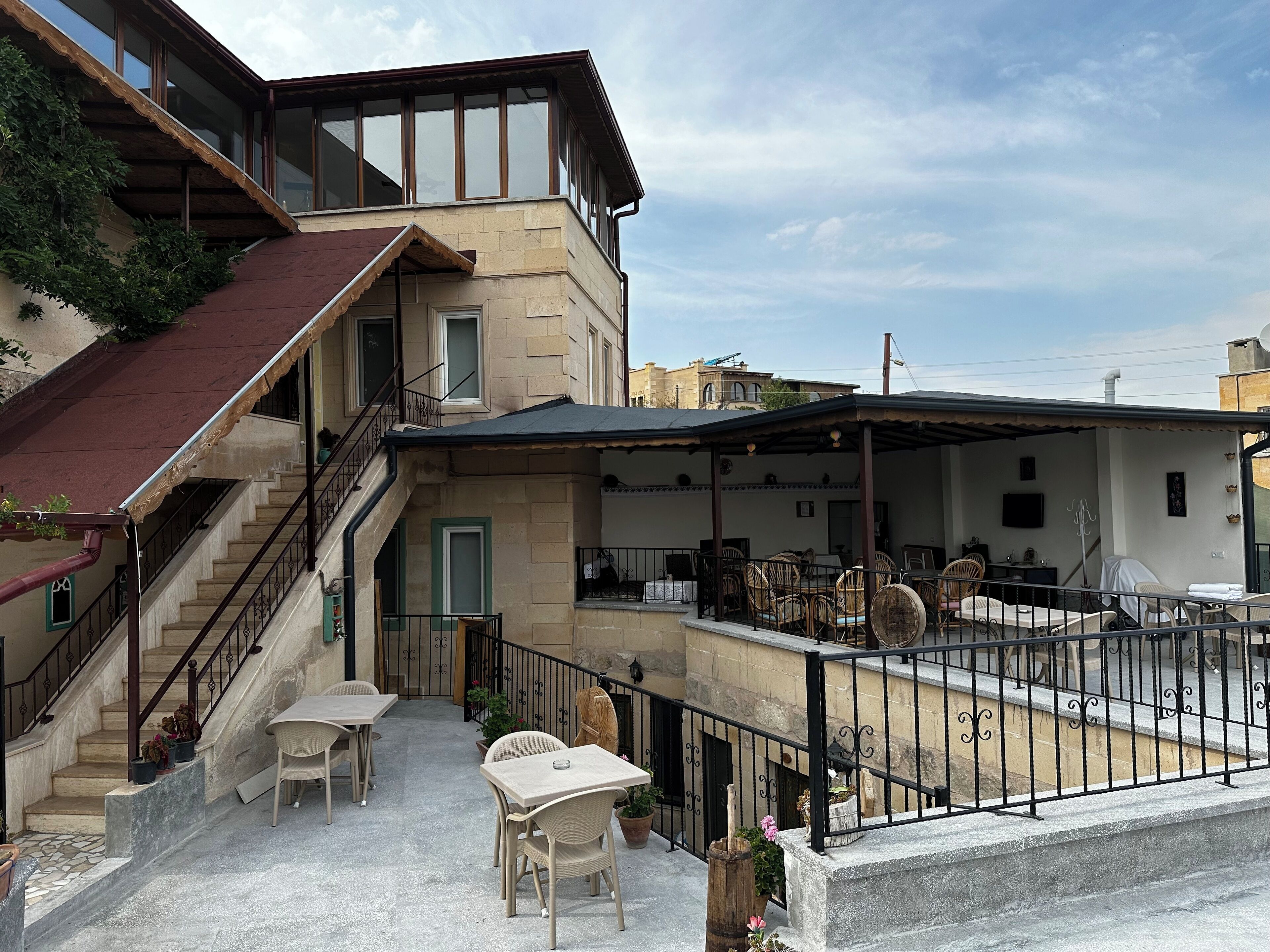 Ein zweistöckiges Gebäude mit einer überdachten Terrasse, die Gartenmöbel und eine Treppe beinhaltet.