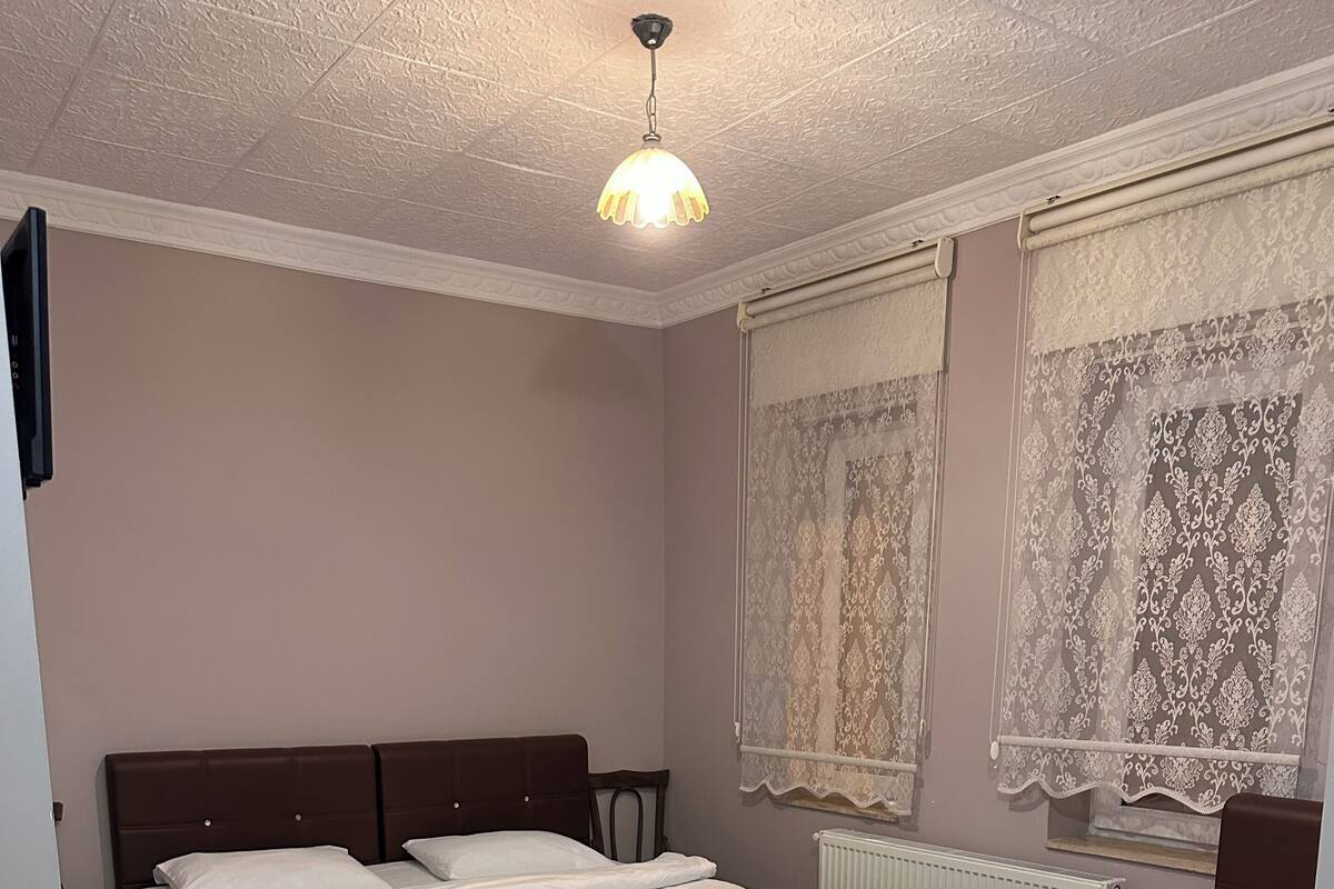 Un dormitorio con dos camas, ventilador de techo y cortinas de encaje.