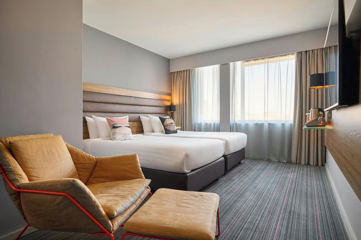 A hotel room with a large bed, a chair, and a TV.