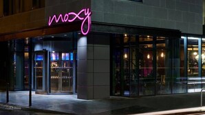 Un edificio con un letrero de neón que dice "mozy" y una entrada de vidrio.