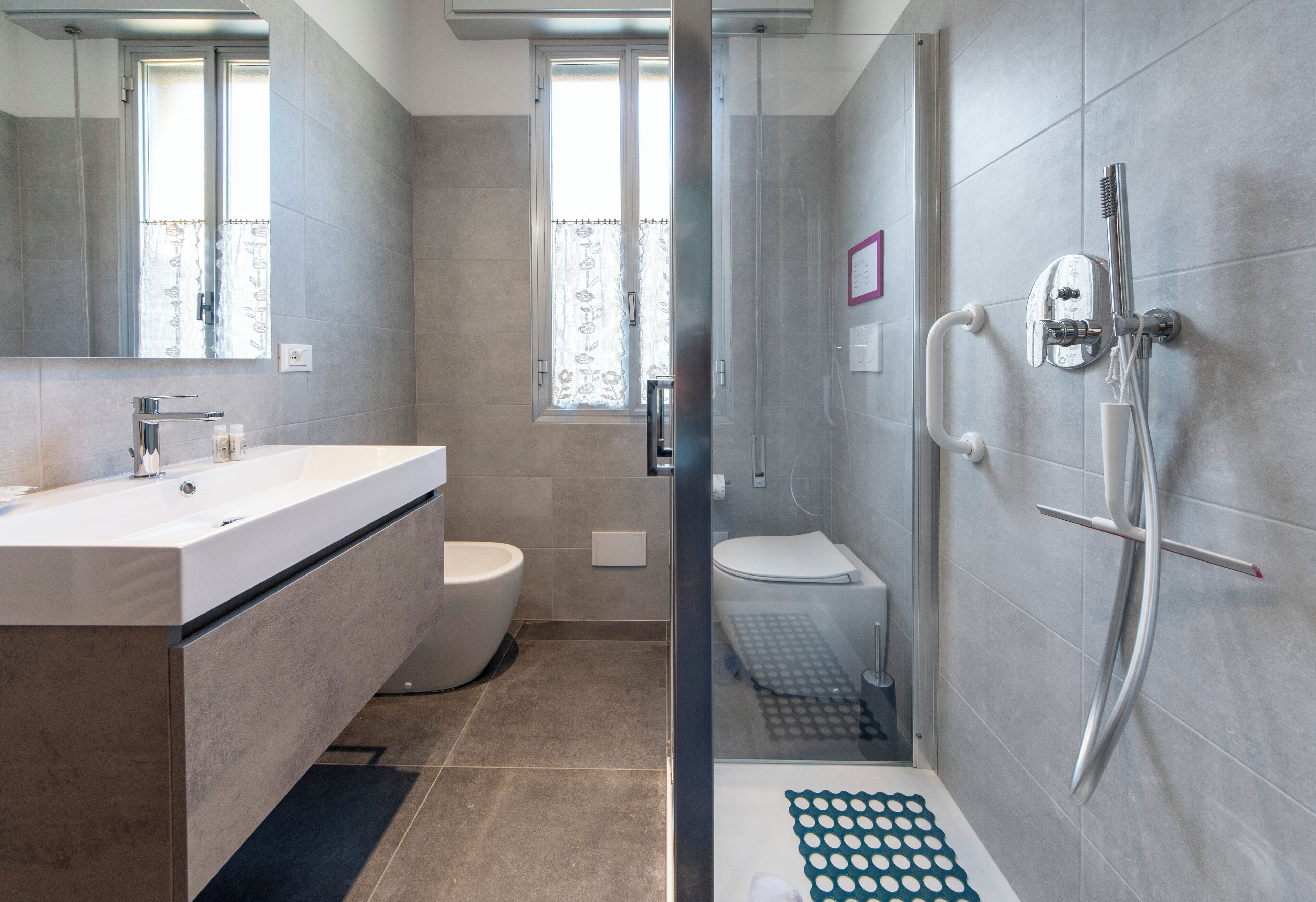 A modern bathroom with a glass-enclosed shower, a white sink, and a toilet.