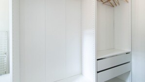 Un placard blanc avec des cintres en bois et une étagère blanche.