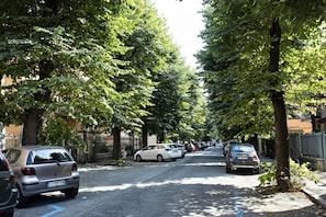 A tree-lined street with parked cars and buildings in the background. - HouSmart Bondi 61 (Bologna)