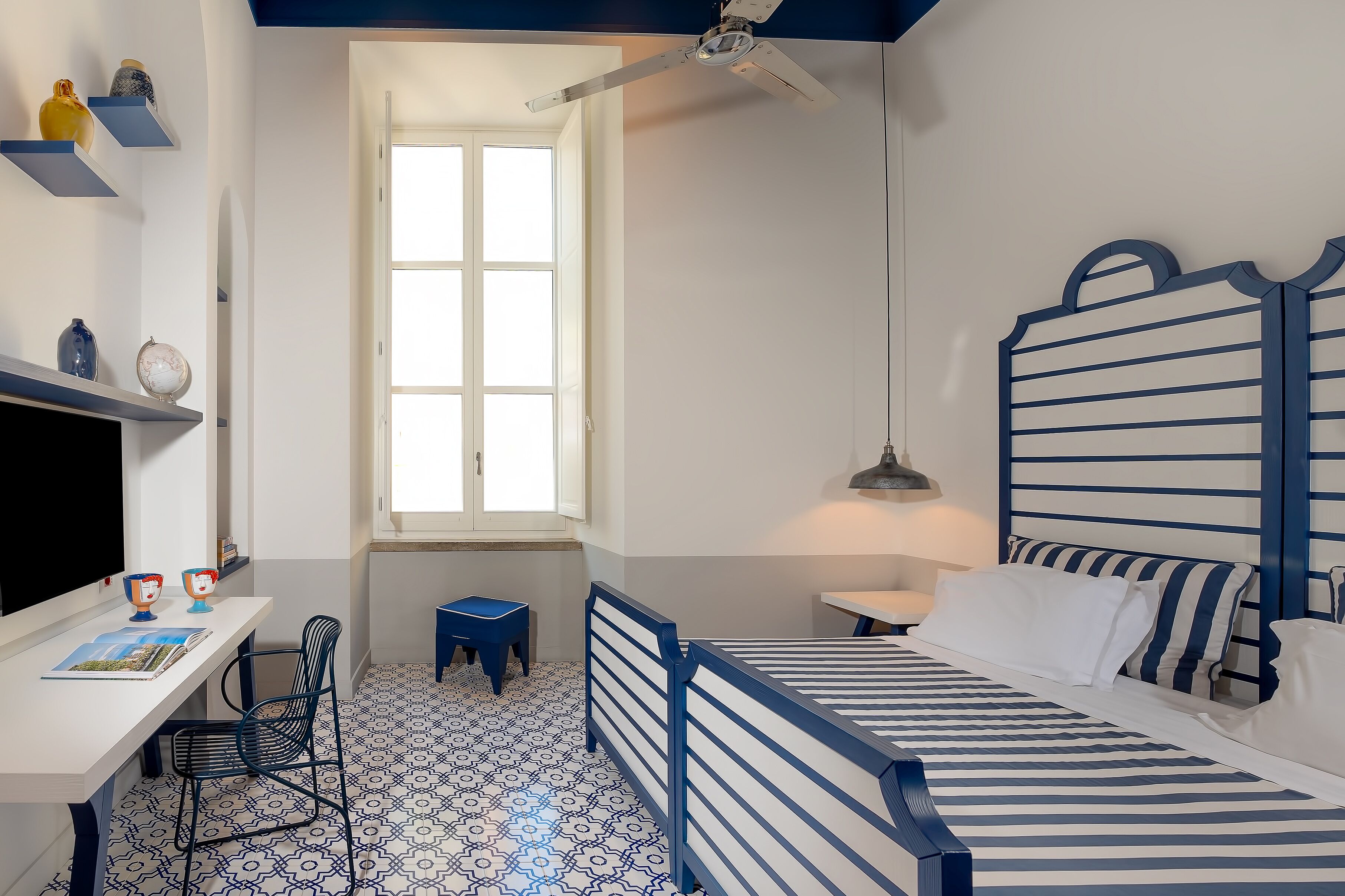 A bedroom with a bed, desk, chair, and a window.