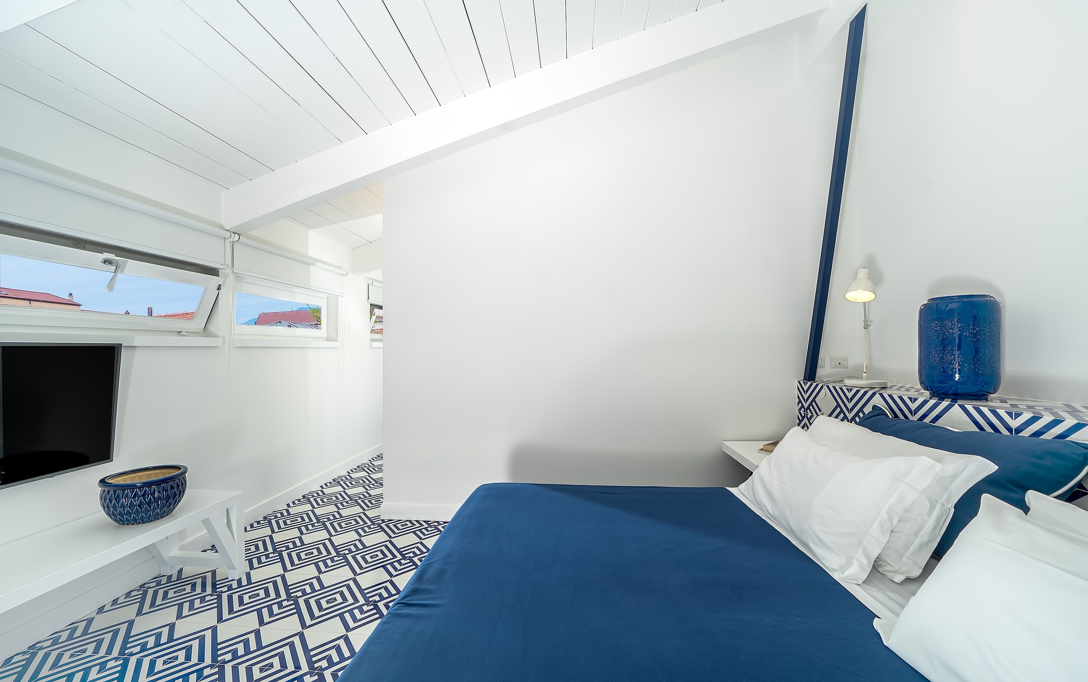 A bedroom with a bed, a window, a bowl, and a lamp.