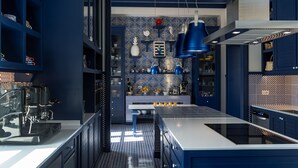 A modern kitchen with blue cabinetry, a central island, and a patterned backsplash. - Maison il Conservatorio (Sorrento)