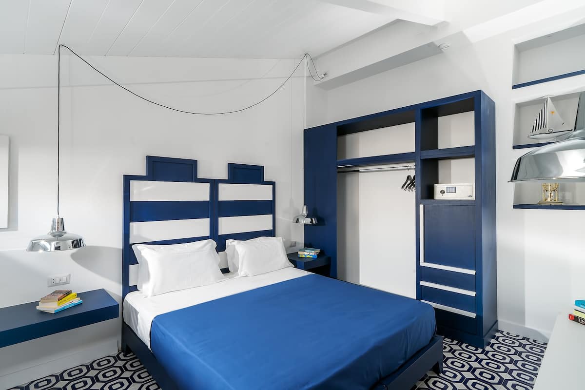 Moderni hotellihuone, jossa on suuri sänky, työpöytä ja vaatekaappi.