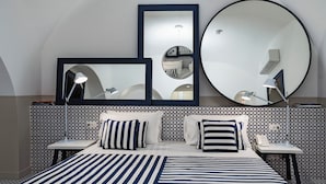 A modern hotel room with a large bed, two bedside tables, a round mirror, and a patterned wall. - Maison il Conservatorio (Sorrento)