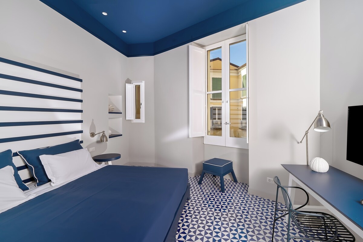 Une chambre à coucher moderne avec un lit, un bureau, une chaise et une fenêtre.