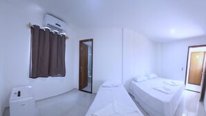 Habitación de hotel con dos camas, una mesita de noche pequeña, un calentador y un espejo.