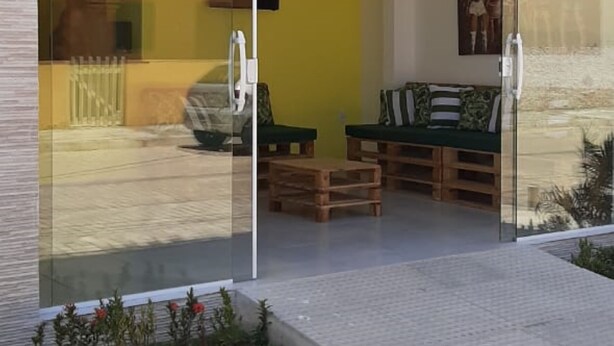 Un edificio moderno con entrada de cristal, interior amarillo y mesas al aire libre.
