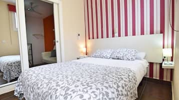 A bedroom with a bed, a nightstand, a mirror, and a striped wall.