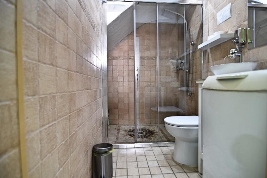A bathroom with a glass-enclosed shower, a toilet, and a sink.