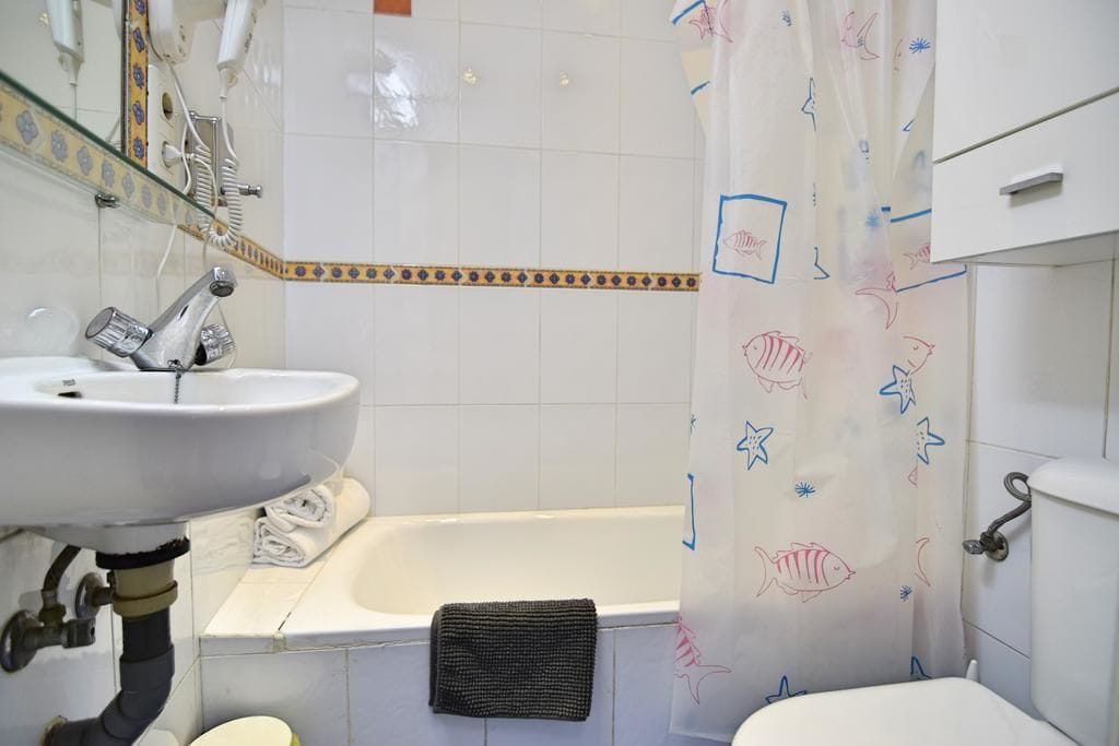 A bathroom with a white sink, a bathtub, and a toilet.