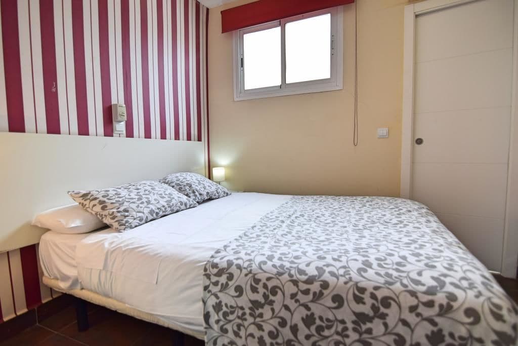 Un dormitorio con cama, pared a rayas, ventana y puerta.