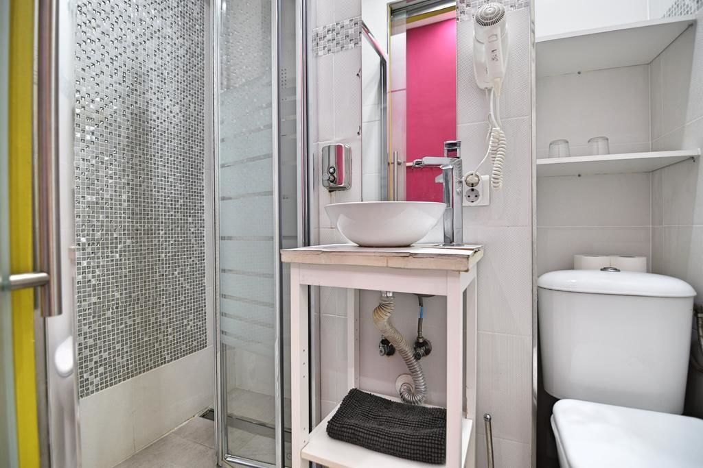 Un baño con cabina de ducha de vidrio, un lavabo blanco, un espejo rosa y un inodoro blanco.