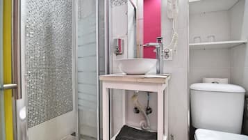 Un baño con cabina de ducha de vidrio, un lavabo blanco, un espejo rosa y un inodoro blanco.