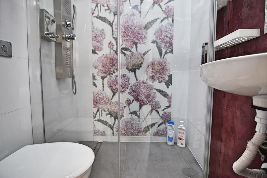 Een badkamer met toilet, een douche met glazen deur en een wastafel.