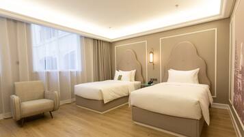 Habitación de hotel con dos camas, una silla y un ventanal grande.