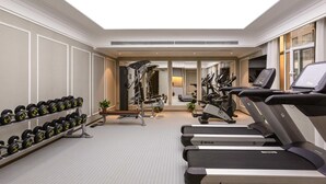 Un gimnasio con cintas de correr, mancuernas y máquinas de pesas.