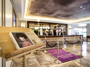 A reception desk with a book titled 'Impressionism' placed on a wooden stand. - Mercure Taiyuan E Tech (Taiyuan)