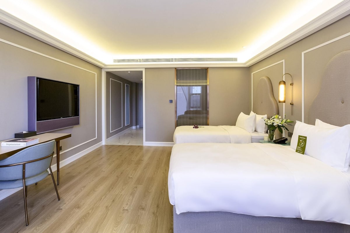 Una habitación de hotel con televisión, dos camas, un escritorio y una silla.