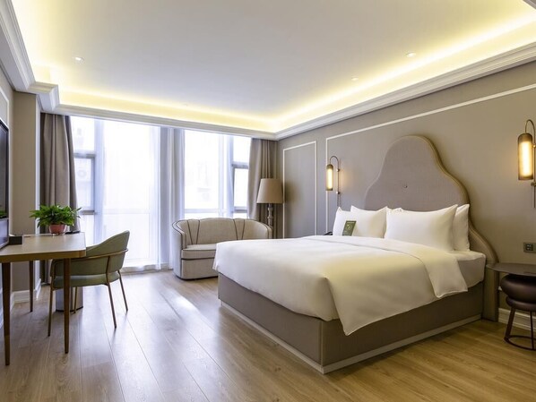 Une chambre d’hôtel moderne équipée d’un grand lit, d’un bureau, d’une chaise et d’un canapé.